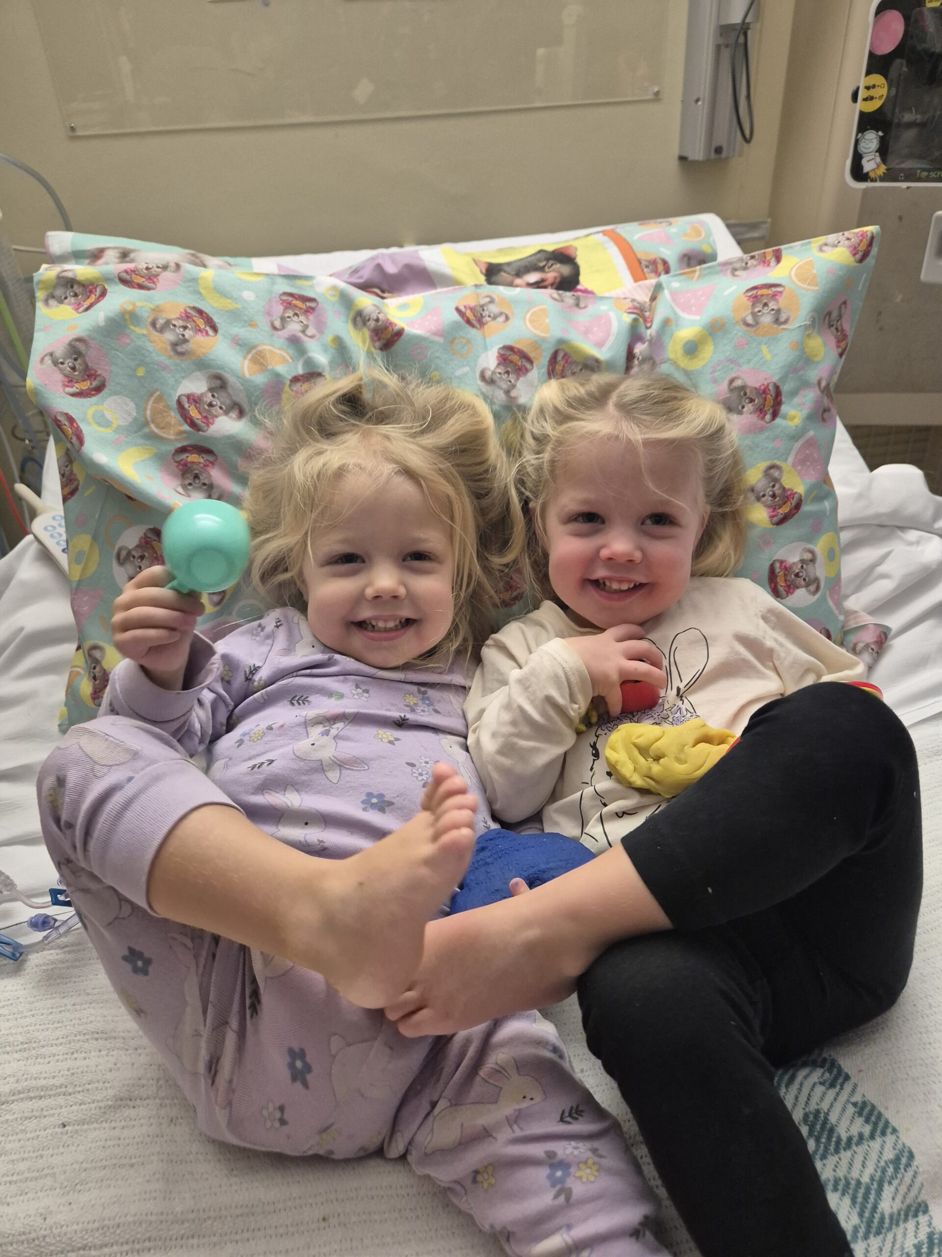 Smiling twins supported by Ronald McDonald House Greater Western Sydney in a hospital bed