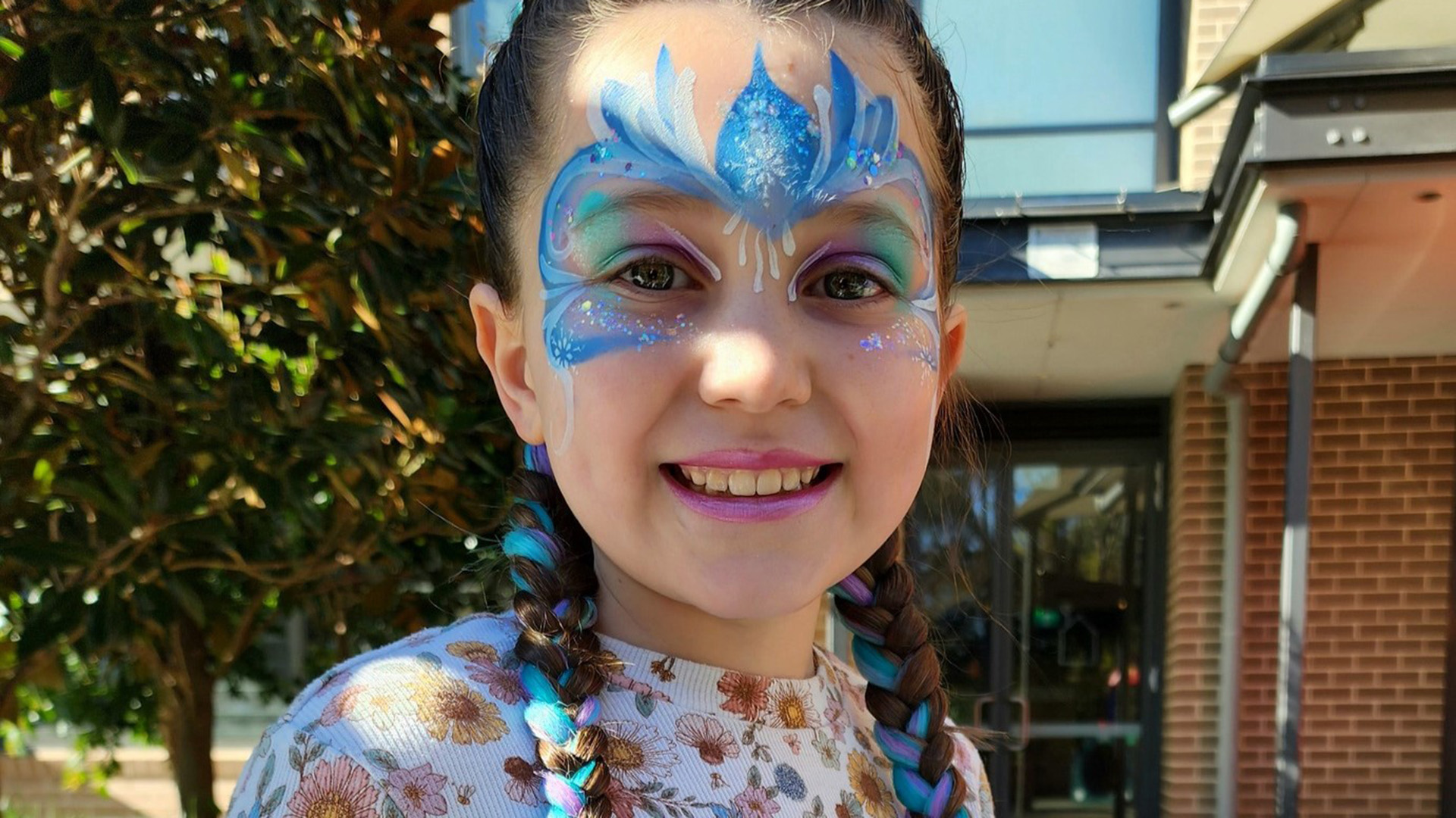 Young girl at Ronald McDonald House Greater Western Sydney Westmead holding up a sign in the shape of a heart that says "Home away from home"