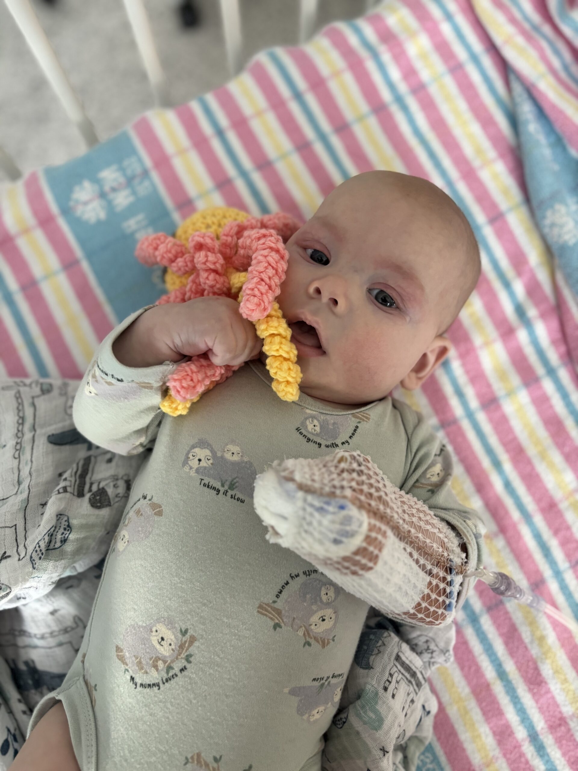 Baby clutching a crocheted octopus plush toy from the Ronald McDonald House Greater Western Sydney Hospitality Cart at Campbelltown Hospital